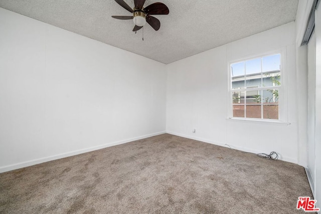 carpeted spare room with ceiling fan and a textured ceiling