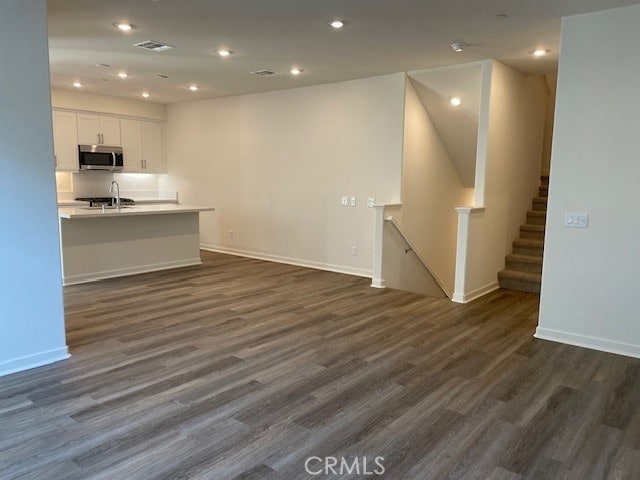 unfurnished living room with dark wood-type flooring and sink