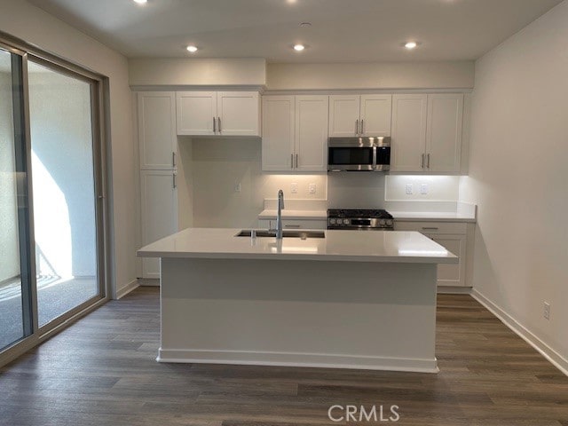 kitchen with a center island with sink, sink, stainless steel appliances, white cabinets, and dark hardwood / wood-style flooring