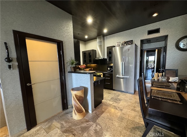 kitchen with stainless steel fridge and wall chimney range hood