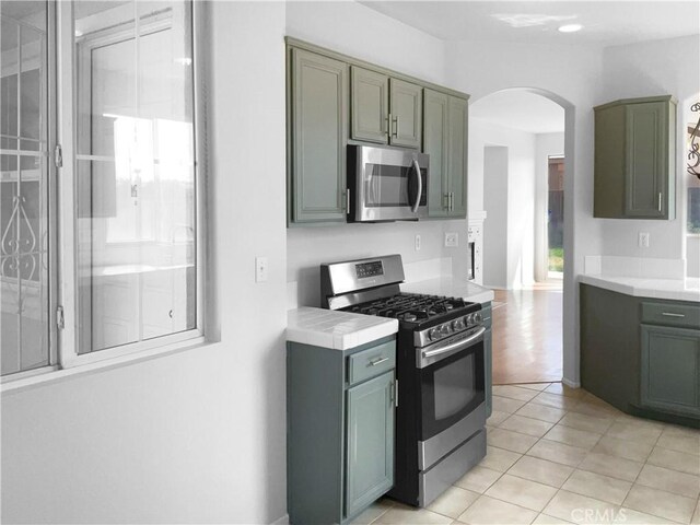 kitchen with light tile patterned floors, stainless steel appliances, and green cabinets