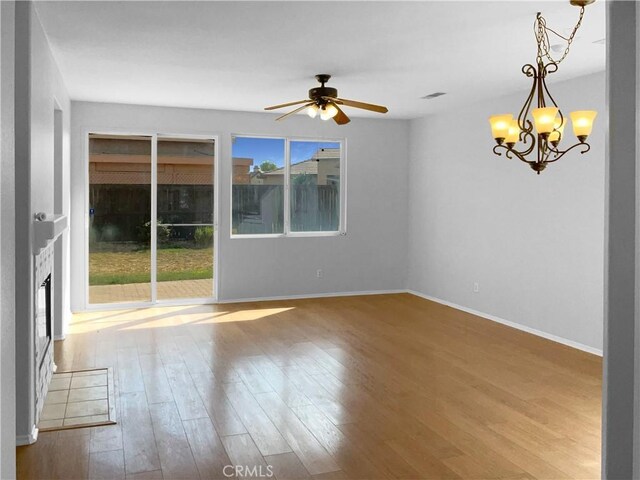 unfurnished room with ceiling fan with notable chandelier and hardwood / wood-style flooring