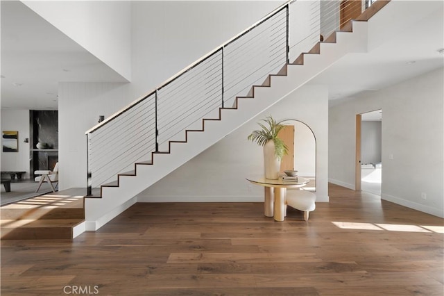 stairway featuring wood-type flooring and a high ceiling