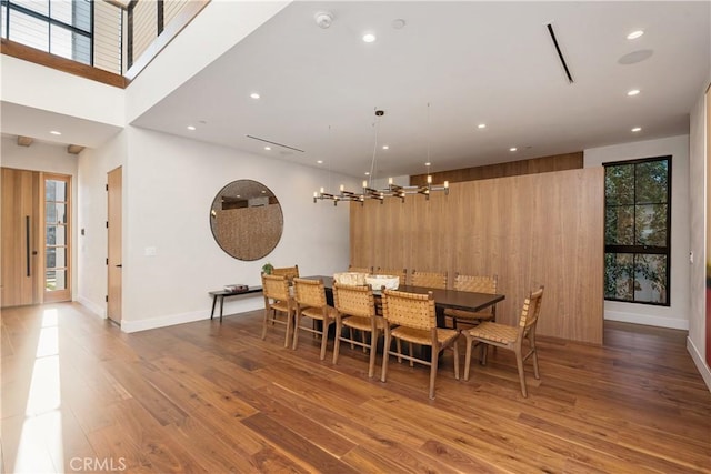 dining space featuring wood walls, a towering ceiling, dark wood-type flooring, and a wealth of natural light