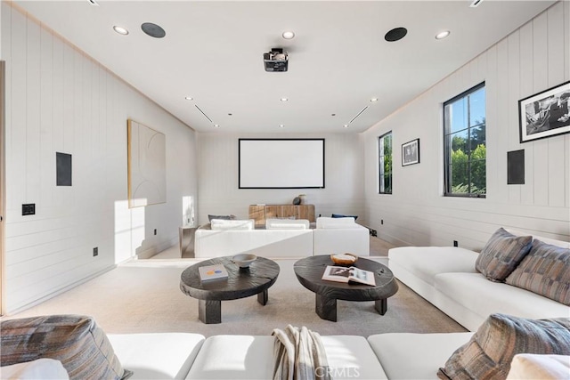 home theater room with light carpet and wood walls