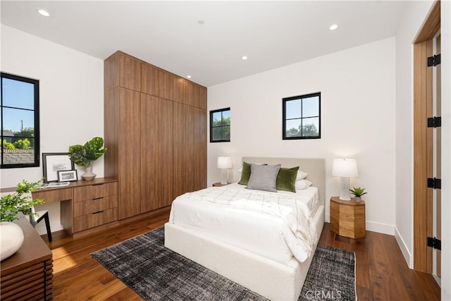 bedroom featuring multiple windows, built in desk, and dark hardwood / wood-style floors