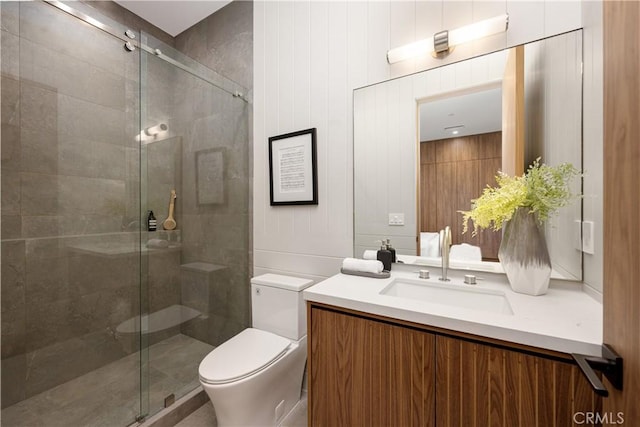 bathroom with a shower with door, vanity, and toilet