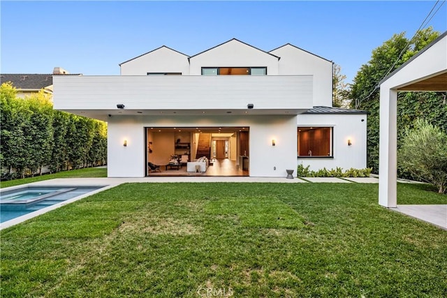 back of house featuring an in ground hot tub and a lawn