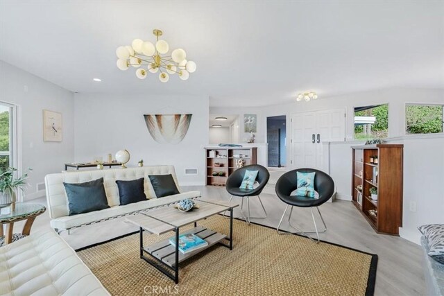 living room with an inviting chandelier, plenty of natural light, and light hardwood / wood-style floors