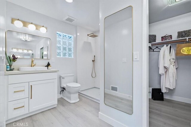 bathroom featuring vanity, wood-type flooring, toilet, and walk in shower