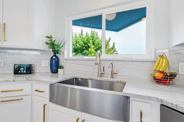 kitchen with backsplash, light stone countertops, sink, and white cabinets