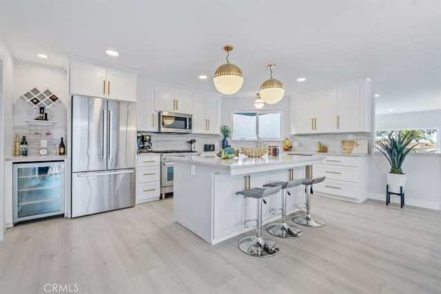 kitchen with white cabinets, appliances with stainless steel finishes, decorative light fixtures, wine cooler, and decorative backsplash