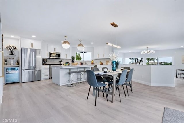 dining room featuring light wood-type flooring, sink, and a chandelier