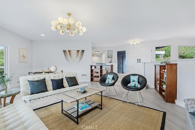 living room featuring plenty of natural light, a chandelier, and light hardwood / wood-style floors