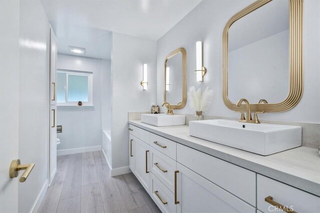 bathroom with vanity, hardwood / wood-style floors, a bathtub, and toilet