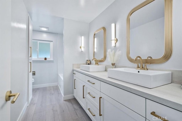 bathroom featuring hardwood / wood-style flooring, vanity, a bathtub, and toilet