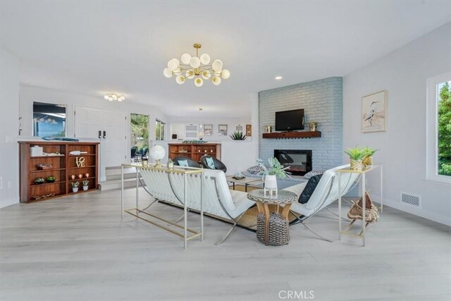 living room featuring an inviting chandelier, a fireplace, and light hardwood / wood-style flooring