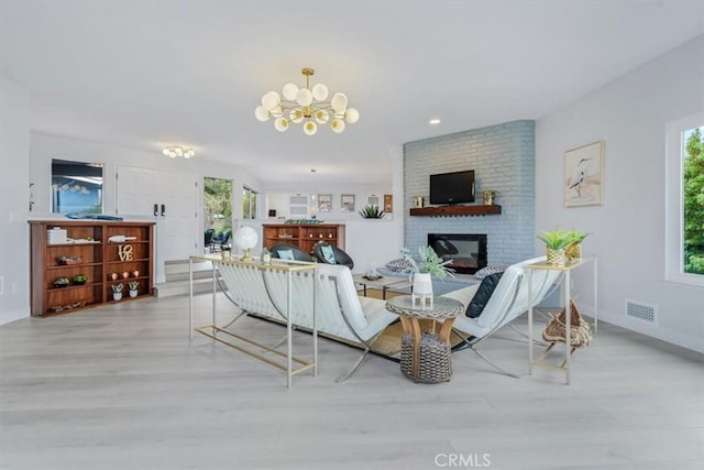 living room featuring light wood-type flooring, a chandelier, and a fireplace