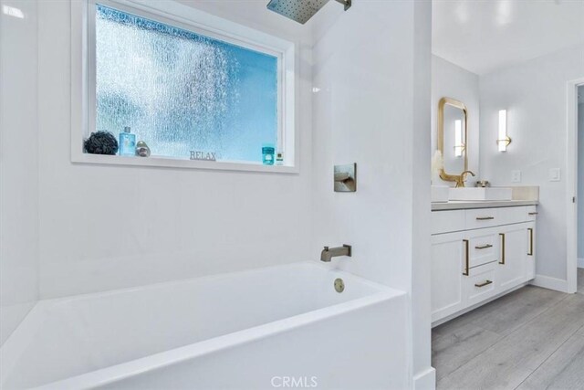 bathroom featuring vanity, hardwood / wood-style floors, and washtub / shower combination