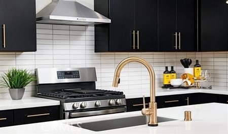 kitchen with decorative backsplash, wall chimney range hood, and stainless steel gas range oven