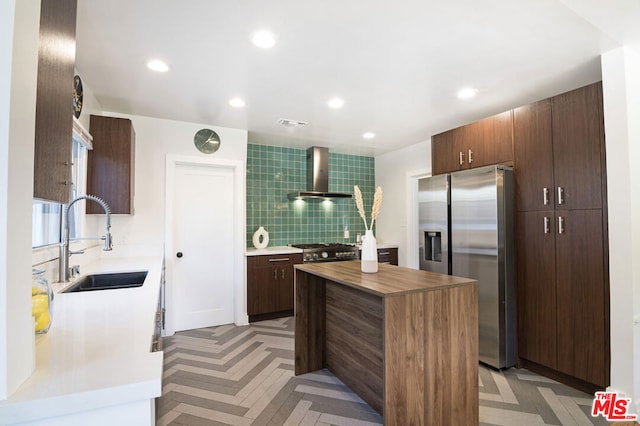 kitchen with sink, a center island, wall chimney range hood, decorative backsplash, and appliances with stainless steel finishes