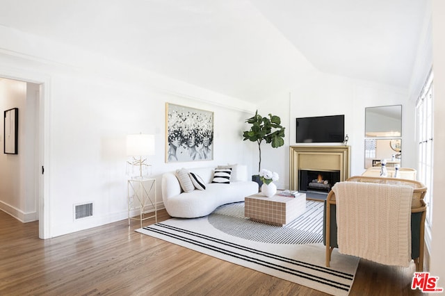 living room featuring wood-type flooring and vaulted ceiling