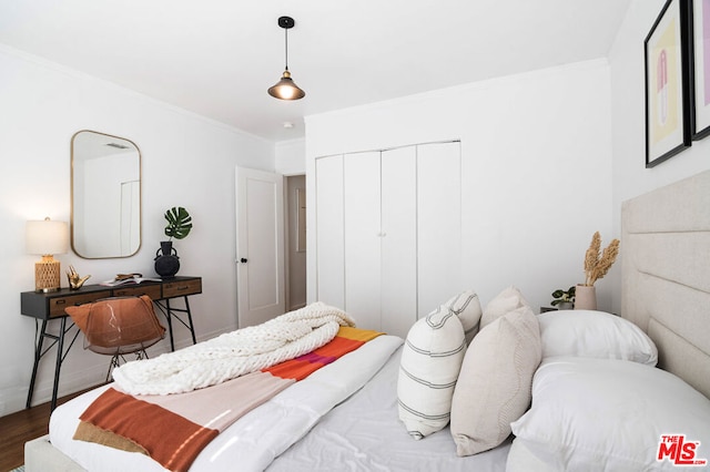 bedroom with crown molding, a closet, and dark wood-type flooring