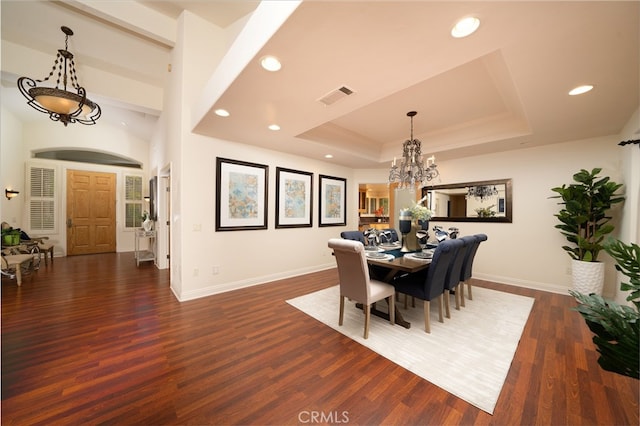 dining area with a notable chandelier, a raised ceiling, and dark hardwood / wood-style flooring