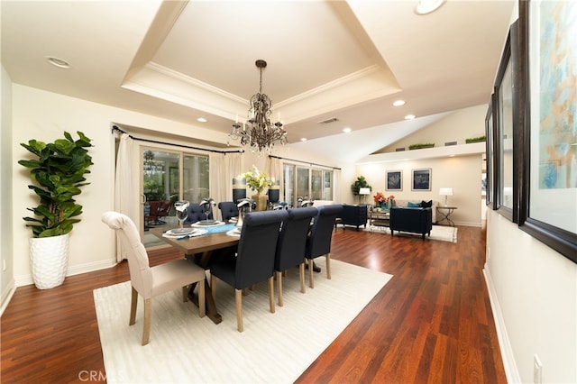 dining area with ornamental molding, a tray ceiling, dark wood-type flooring, and a chandelier