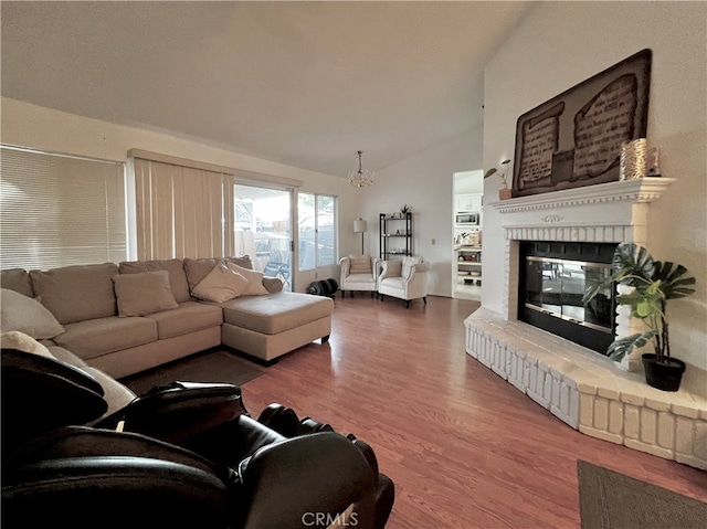 living room with dark wood-type flooring, a fireplace, a chandelier, and lofted ceiling