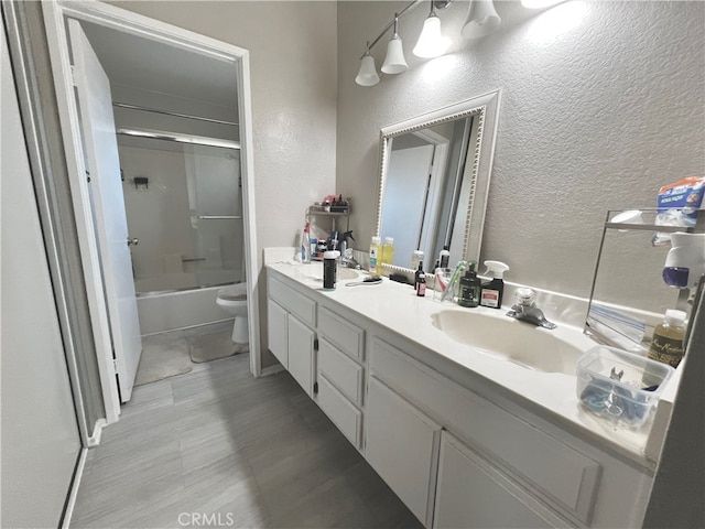 full bathroom featuring shower / bath combination with glass door, vanity, and toilet