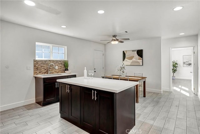 kitchen featuring a center island, sink, backsplash, ceiling fan, and dark brown cabinets