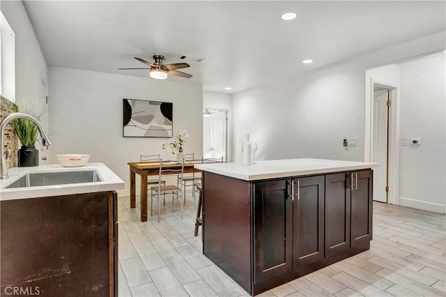 kitchen featuring ceiling fan, dark brown cabinets, sink, and a center island