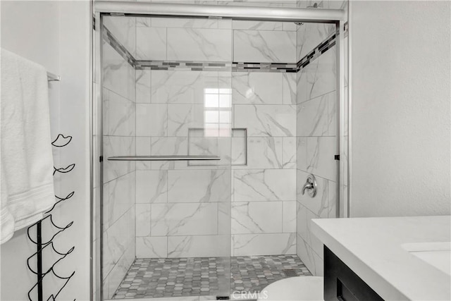 bathroom with a shower with shower door, toilet, and vanity