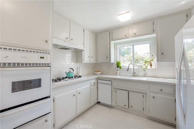 kitchen with tasteful backsplash, sink, white cabinets, and white appliances