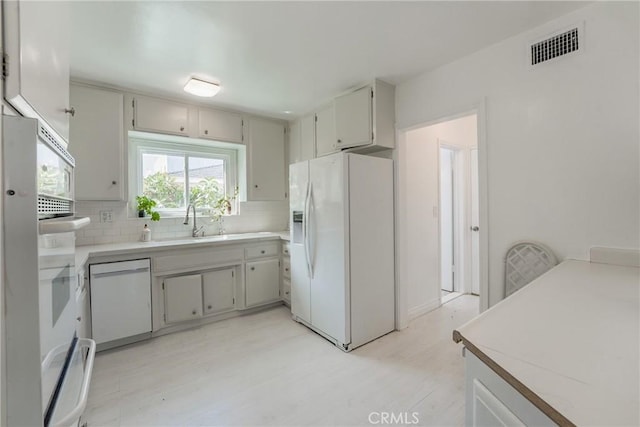 kitchen featuring decorative backsplash, sink, white appliances, and light hardwood / wood-style flooring