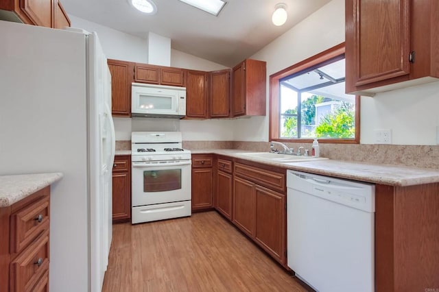 kitchen with vaulted ceiling, sink, light hardwood / wood-style flooring, and white appliances