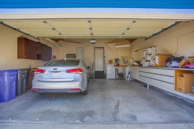 garage with washing machine and dryer and a garage door opener