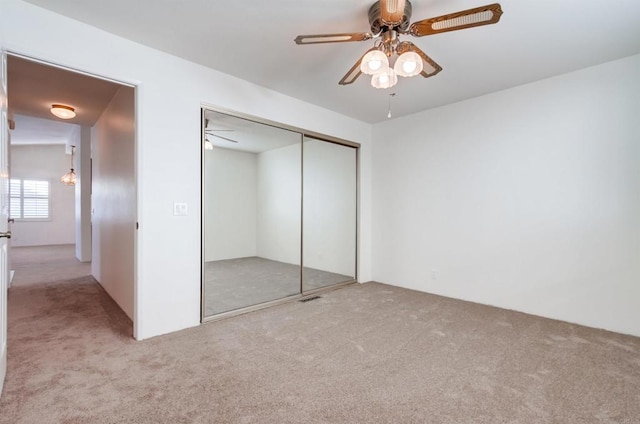 unfurnished bedroom with ceiling fan, a closet, and light carpet