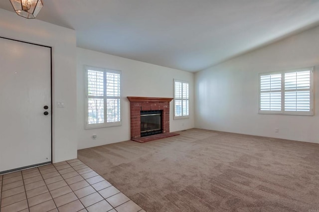 unfurnished living room featuring vaulted ceiling, light colored carpet, and a fireplace