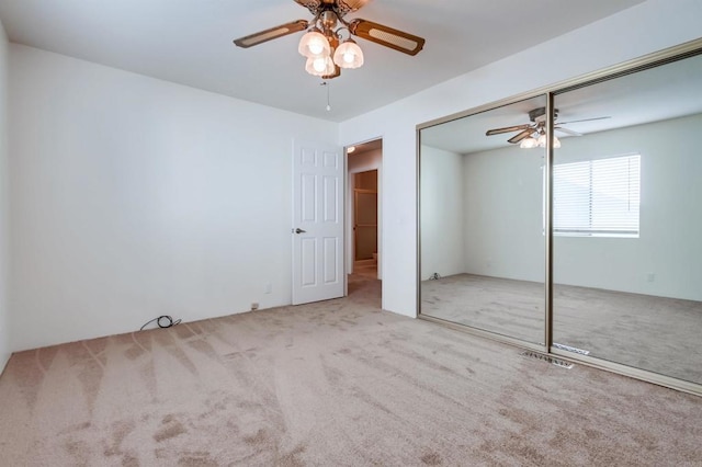 unfurnished bedroom featuring ceiling fan, light colored carpet, and a closet