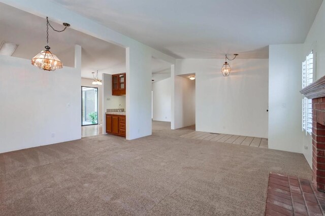 unfurnished living room with light carpet, a fireplace, an inviting chandelier, and lofted ceiling