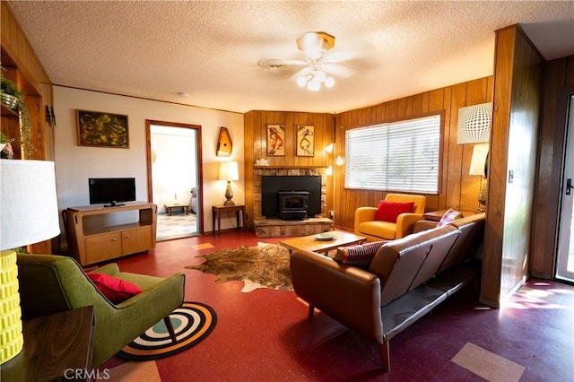 living room featuring a textured ceiling, a wood stove, and wooden walls