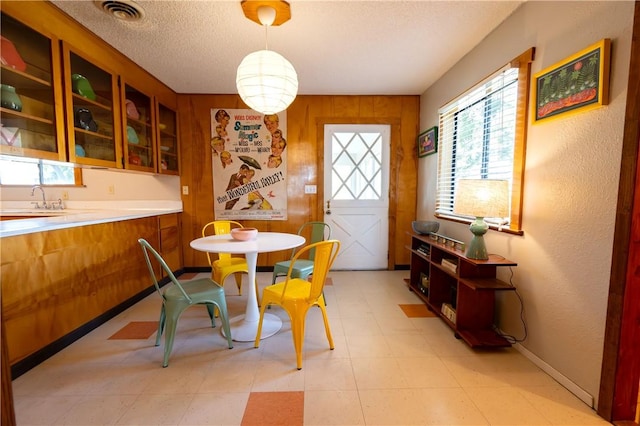 dining room with wooden walls, sink, and a textured ceiling