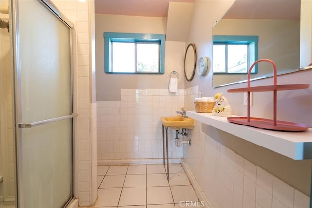 bathroom featuring tile patterned floors, a shower with shower door, and tile walls