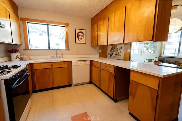 kitchen with a textured ceiling, sink, a healthy amount of sunlight, and white appliances