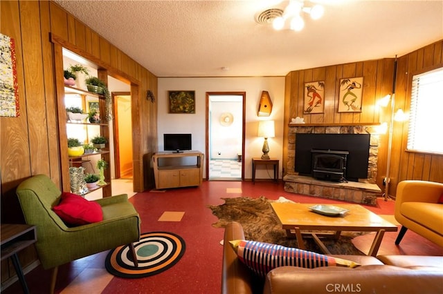 living room featuring wood walls, a wood stove, and a textured ceiling