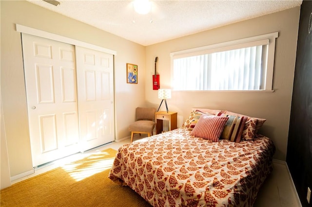 bedroom with carpet flooring, a textured ceiling, a closet, and ceiling fan