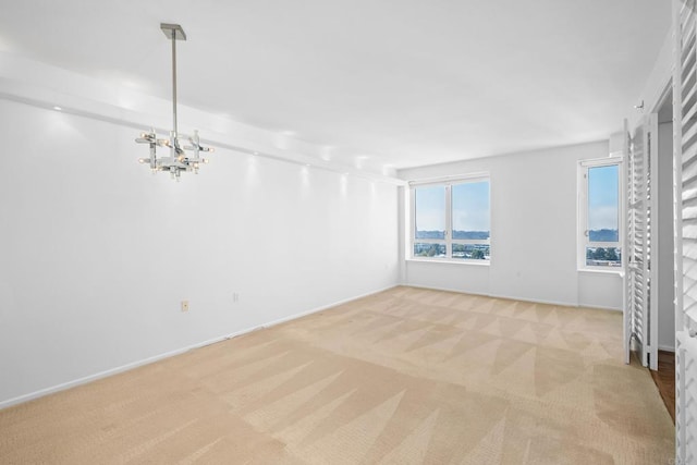 carpeted empty room with an inviting chandelier