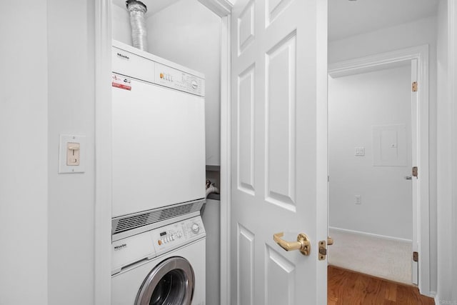 clothes washing area featuring stacked washer / dryer and wood-type flooring